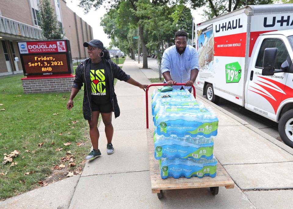 School Board member Aisha Carr, left, and Darrin Madison, with Urban Underground, deliver donated cases of bottled water to Andrew Douglas Middle School on North 18th Street in Milwaukee on Thursday, Aug. 26, 2021.