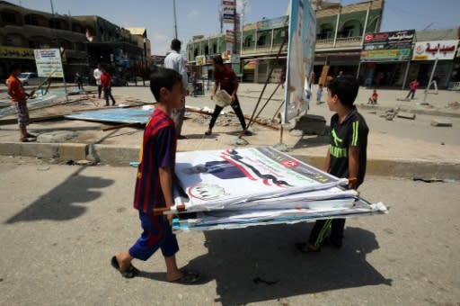 Iraqi youth dismantle campaign posters in the city of Mosul on May 12, 2018, as they collect the scrap metal to sell