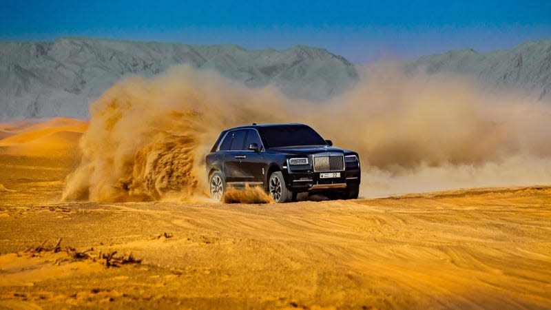 A black Rolls-Royce Cullinan driving through a desert