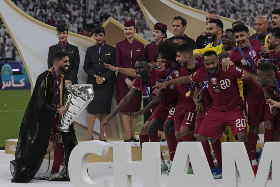 Qatar's Hasan Al Haydos holds the trophy and walks towards his teammates at the end of the Asian Cup final soccer match between Qatar and Jordan at the Lusail Stadium in Lusail, Qatar, Saturday, Feb. 10, 2024. (AP Photo/Thanassis Stavrakis)