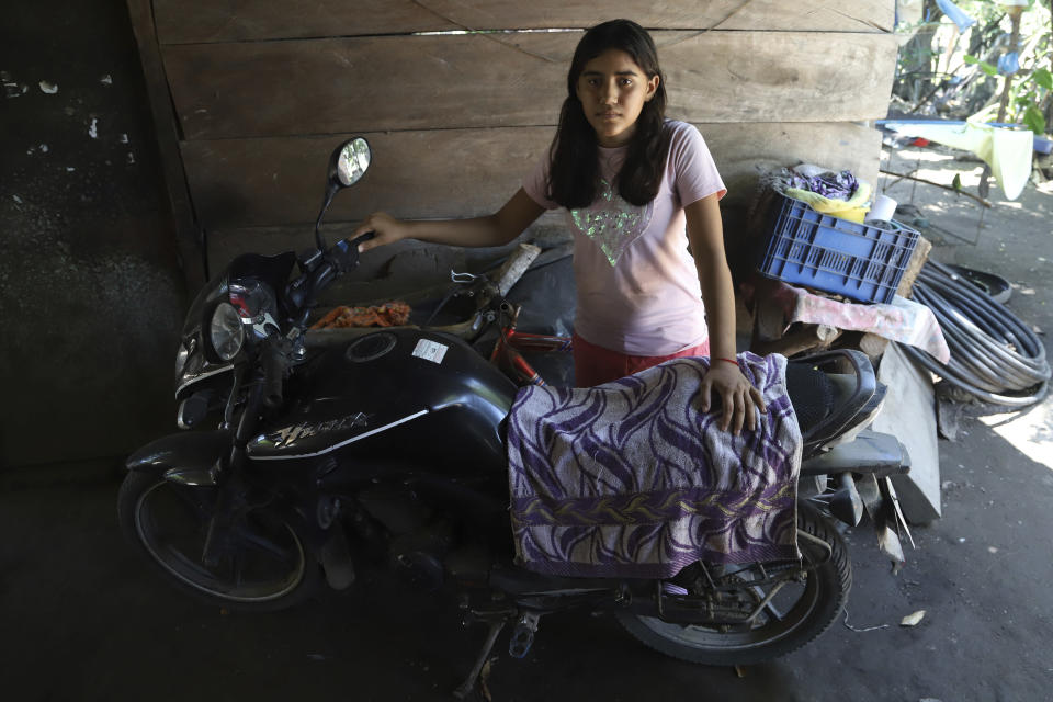 Abigail Pena, Esmeralda Dominguez's eldest daughter, poses for a photo with her mother's motorcycle, parked at their home in the Sisiguayo community in Jiquilisco, in the Bajo Lempa region of El Salvador, Thursday, May 12, 2022. Dominguez, a rural community leader and mother of two, including a 4-month-old daughter, is one of thousands arrested in the past eight weeks since the congress granted President Nayib Bukele a state of emergency declaration suspending some civil liberties after street gangs killed dozens of people in late March. (AP Photo/Salvador Melendez)