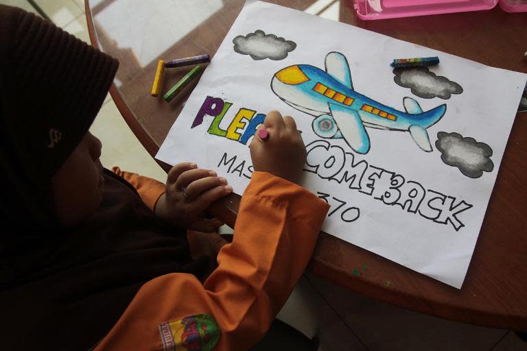 An Indonesian student writes a message expressing prayers and well-wishes for passengers onboard missing Malaysia Airlines (MAS) flight MH370 in Medan, North Sumatra, on March 15, 2014