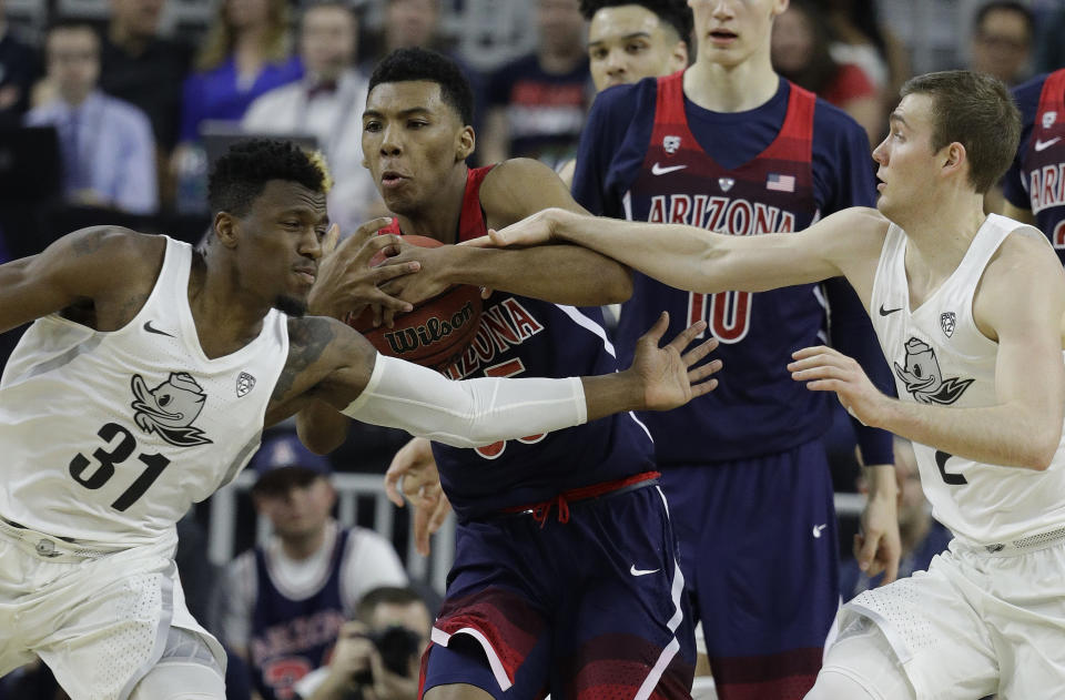 Arizona's Allonzo Trier, center, competes for the ball with Oregon's Dylan Ennis, left, and Casey Benson during the first half of an NCAA college basketball game for the championship of the Pac-12 men's tournament Saturday, March 11, 2017, in Las Vegas. (AP Photo/John Locher)