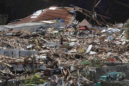 A survivor walks on debris of houses destroyed after super Typhoon Haiyan battered Tacloban city