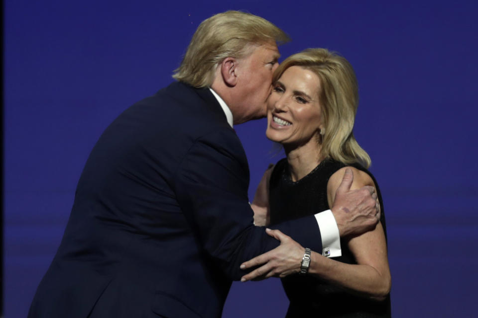 FILE - President Donald Trump gives Laura Ingraham a kiss after inviting her on stage during the Turning Point USA Student Action Summit at the Palm Beach County Convention Center, on Dec. 21, 2019, in West Palm Beach, Fla. The revelation that Fox News Channel personalities sent text messages to the White House during the Jan. 6 insurrection urging President Donald Trump to call off the attack is the latest example of the network's stars seeking to influence the actions of newsmakers instead of simply reporting the news.(AP Photo/Luis M. Alvarez, File)