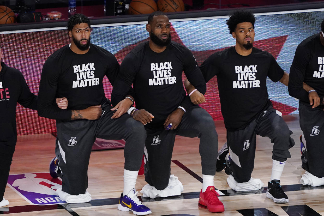 LAKE BUENA VISTA, FLORIDA - AUGUST 01: (L-R) Anthony Davis #3, LeBron James #23 and Quinn Cook #28 of the Los Angeles Lakers take a kneel before an NBA basketball game against the Toronto Raptors at The Arena in the ESPN Wide World Of Sports Complex on August 1, 2020 in Lake Buena Vista, Florida. NOTE TO USER: User expressly acknowledges and agrees that, by downloading and or using this photograph, User is consenting to the terms and conditions of the Getty Images License Agreement. (Photo by Ashley Landis - Pool/Getty Images)