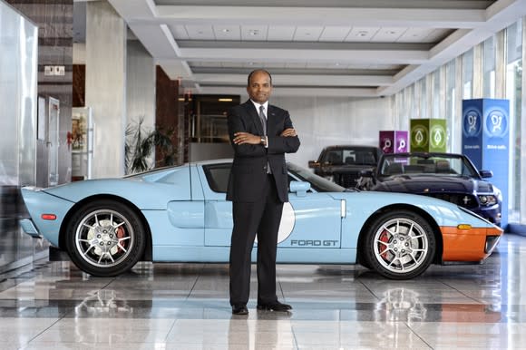 Raj Nair standing in front of a Ford GT sports car with his arms crossed.