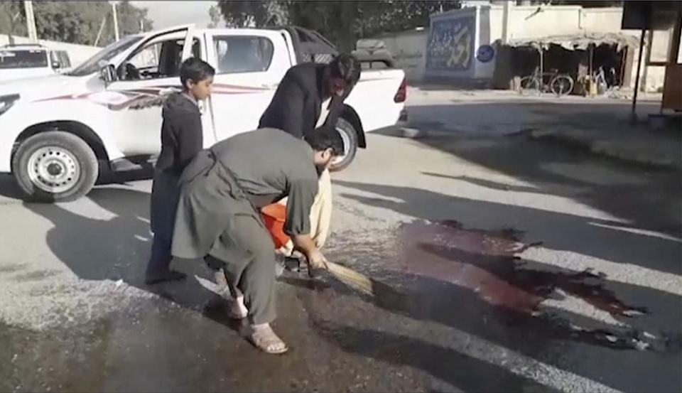 In this image made from video, locals sweep blood at the site of a gun attack on a Japanese aid worker's truck Wednesday, Dec. 4, 2019, Nangarhar province, easter Afghanistan. Japanese physician and aid worker Tetsu Nakamura has died of his wounds after an attack that also killed five Afghans, including the doctor’s bodyguards, the driver and a passenger. (AP Photo)