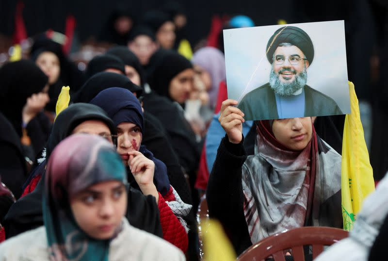 FILE PHOTO: A supporter of Lebanon's Hezbollah leader Sayyed Hassan Nasrallah holds his picture during a rally in Beirut's southern suburbs