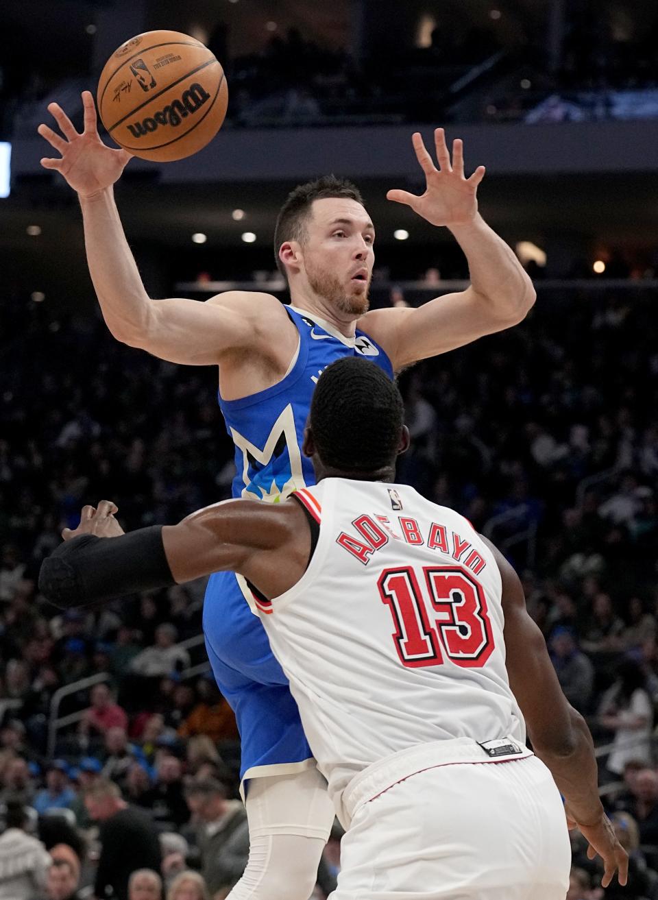 Milwaukee Bucks guard Pat Connaughton passes the ball to a teammate while being defended by Miami Heat center Bam Adebayo during the second half of their game Feb. 4 at Fiserv Forum. The Bucks and Heat square off in the first round of the 2023 NBA playoffs.