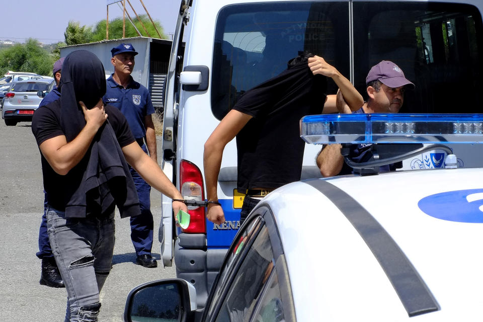 Israeli men cover their faces with their shirts as they arrive at the Famagusta courthouse in Paralamni town, Cyprus, Thursday, July 18, 2019. A Cyprus court has ordered 12 Israelis vacationing on the east Mediterranean island nation to remain in police custody for eight days after a 19-year-old British woman alleged that she was raped. (AP Photo/Petros Karadjias)