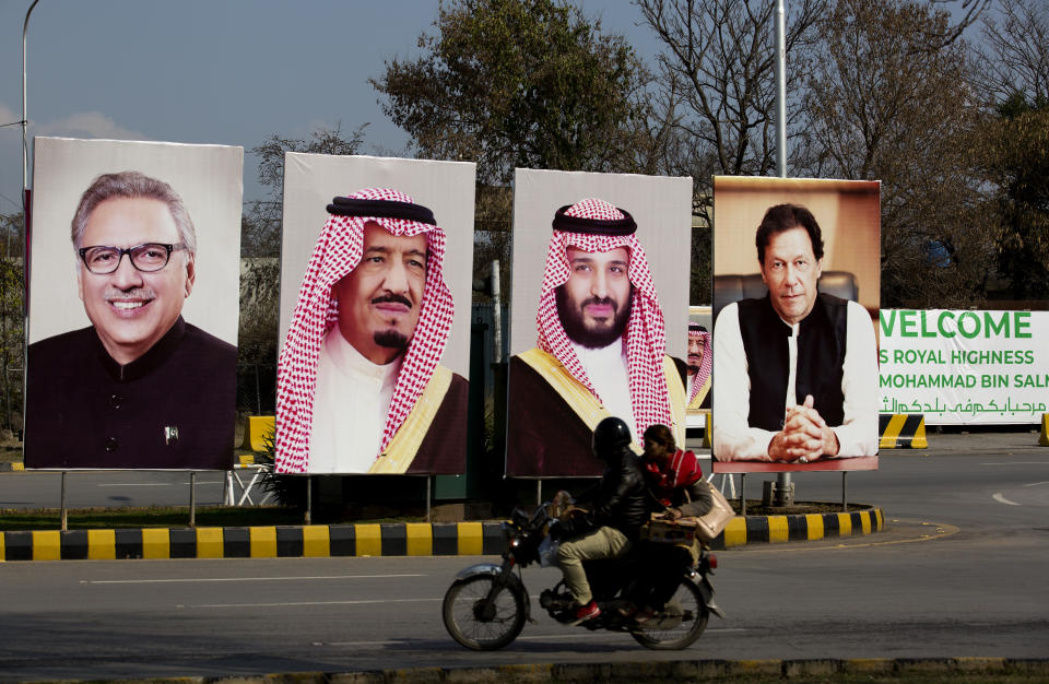 Pakistani riders drive past portraits of Pakistani and Saudi leaders display on the occasion of the visit by Saudi Arabia's Crown Prince to Pakistan, in Islamabad, Pakistan, Friday, Feb. 15, 2019. Pakistan said Wednesday that Crown Prince Mohammed bin Salman will arrive in Islamabad later this week on an official visit that is expected to include the signing of agreements for billions of dollars of investment in Pakistan. (AP Photo/B.K. Bangash)