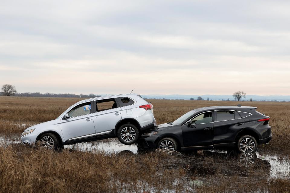 silver car sitting on the hood of a black car in standing water in a field