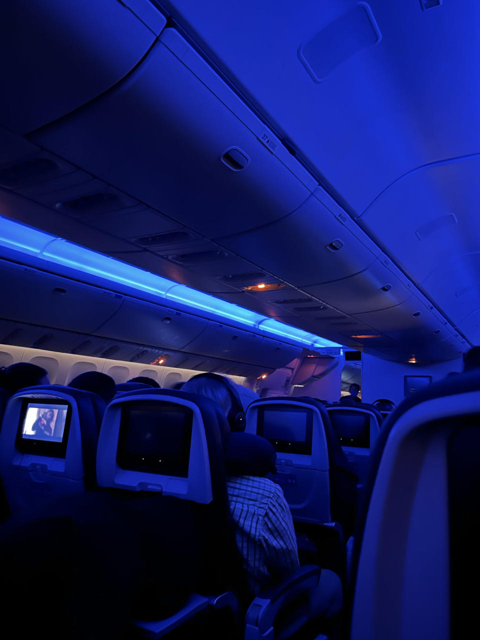 <p>A photo from the iPhone 14 showing an airplane cabin at night, lit only by purple light.</p>
