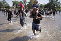 Migrantes centroamericanos cargan a dos niñas mientras corren para cruzar el río Suchiate de Guatemala a México, cerca de Ciudad Hidalgo, México, el lunes 20 de enero de 2020. (AP Foto/Santiago Billy)