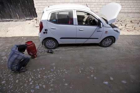 A man uses a cooking gas cylinder to fill Liquefied Petroleum Gas (LPG) into a car at a residential area on the outskirts of Srinagar October 7, 2015. REUTERS/Danish Ismail