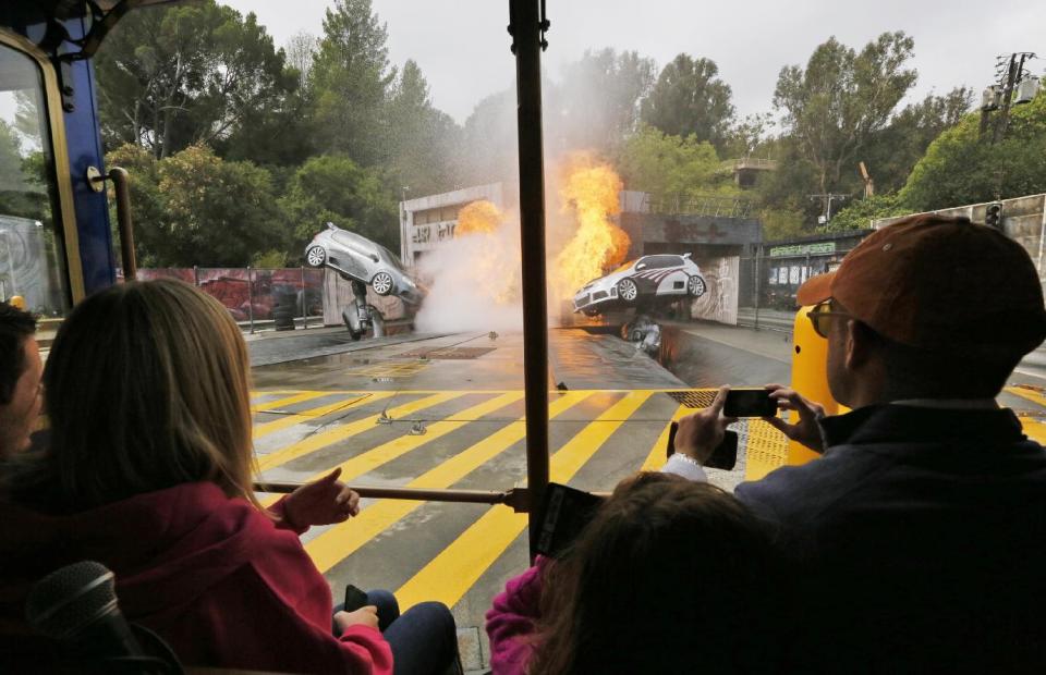 This photo taken Wednesday, June 5, 2013 shows people touring the "Fast and the Furious" Stunt Car attraction at Universal Studios Hollywood's the VIP Experience at Universal Studios Hollywood in Los Angeles. Many theme parks now have VIP tours with perks usually reserved for celebrities _ private tour guides, no waits for the biggest attractions, reserved seating at shows and parades along with behind-the-scenes peaks at places normally off limits. (AP Photo/Damian Dovarganes)