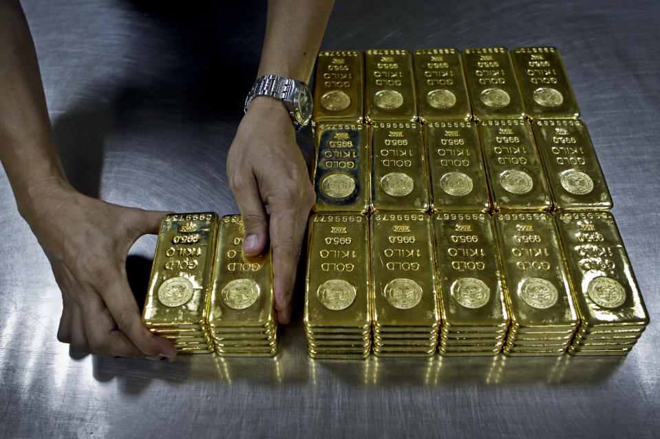 FILE - In this Tuesday Oct. 9, 2012 file photo, a technician prepares 1 Kg gold bars of 995.0 purity to pack for delivery at the Emirates Gold company in Dubai, United Arab Emirates. Safer investments like utilities, gold and government bonds were supposed to flop in 2014 as investors pulled out their money and put it into higher risk, higher growth stocks that benefit from a pickup in the economy. But instead of fading, “safe haven” investments are among the year’s best performers. (AP Photo/Kamran Jebreili, File)