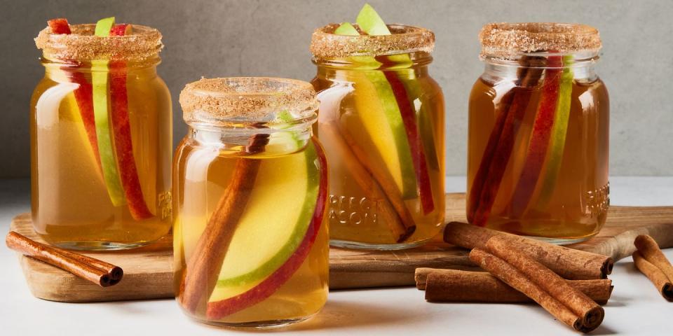 apple pie bourbon shots with apple slices and cinnamon sticks in little mason jars