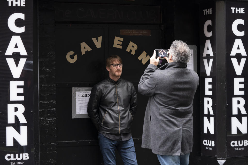 A member of the public poses for a picture outside the Cavern Club in Liverpool, England, Monday Oct. 12, 2020. The British government is set to announce new restrictions on business and socializing in major northern England cities with high infection rates, under a plan to put areas into three tiers. (AP Photo/Jon Super)