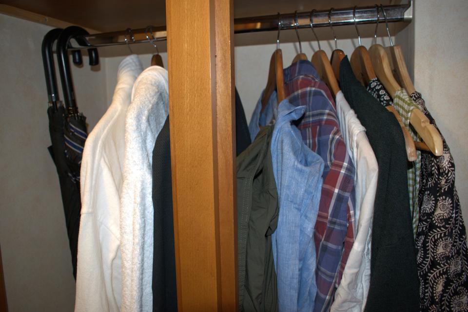 two umbrellas, two robes, and a few shirts hung on hangers in a closet