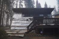 A cabin partially covered in fire-resistant material stands with no visible damage in a neighborhood where most properties were destroyed by the Caldor Fire in Twin Bridges, Calif., Thursday, Sept. 2, 2021. Better weather on Thursday helped the battle against a huge California forest fire threatening communities around Lake Tahoe, but commanders warned firefighters to keep their guard up against continuing dangers. (AP Photo/Jae C. Hong)