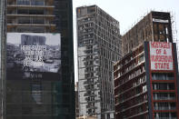 Banners hang on buildings that were damaged during last year's seaport explosion during a commemoration in Beirut, Lebanon, Wednesday, Aug. 4, 2021. Lebanon is marking one year since the horrific explosion at Beirut port. The grim anniversary Wednesday comes amid an unprecedented economic and financial meltdown and a political stalemate that has kept the country without a functioning government for a full year. (AP Photo/Hussein Malla)