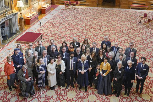 <p>KIRSTY WIGGLESWORTH/POOL/AFP via Getty Images</p> Queen Camilla poses for a group photo at the Windsor Castle reception for the new Miniature Library collection on Jan. 30.