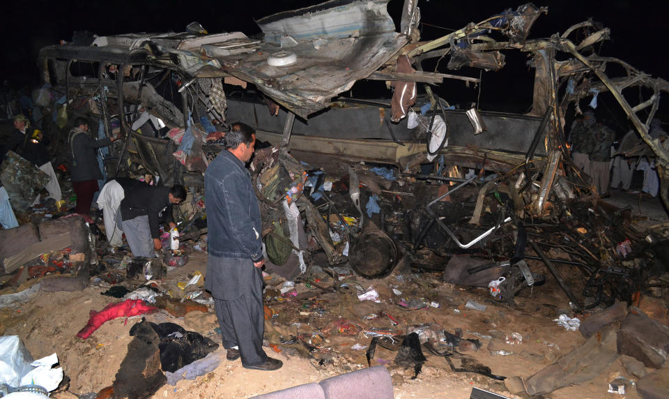 People look at the wreckage of a passenger bus destroyed in a bomb blast in the Mastong district, near Quetta, Pakistan, Tuesday, Jan. 21, 2014. A roadside car bomb hit a bus of Shiite pilgrims returning from Iran, killing several people and wounding many, in restive Baluchistan province, said a top security official. (AP Photo/Arshad Butt)