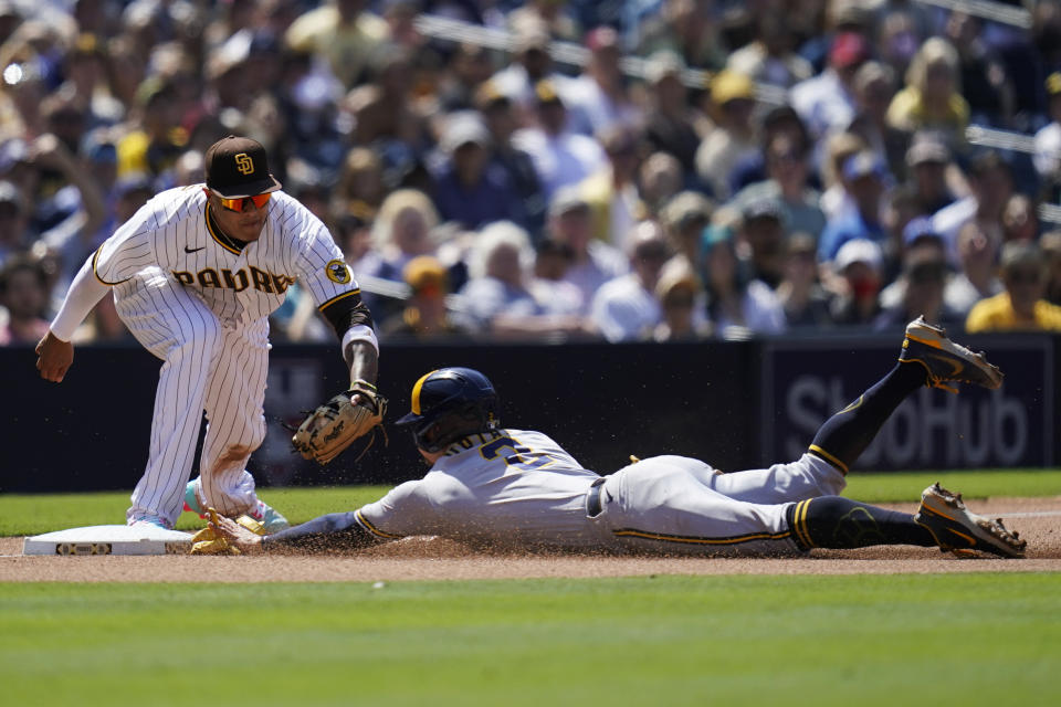 Milwaukee Brewers' Luis Urias, right, arrives safely at third, advancing from first on a single by Andrew McCutchen, as San Diego Padres third baseman Manny Machado is late with the tag during the seventh inning of a baseball game Wednesday, May 25, 2022, in San Diego. (AP Photo/Gregory Bull)