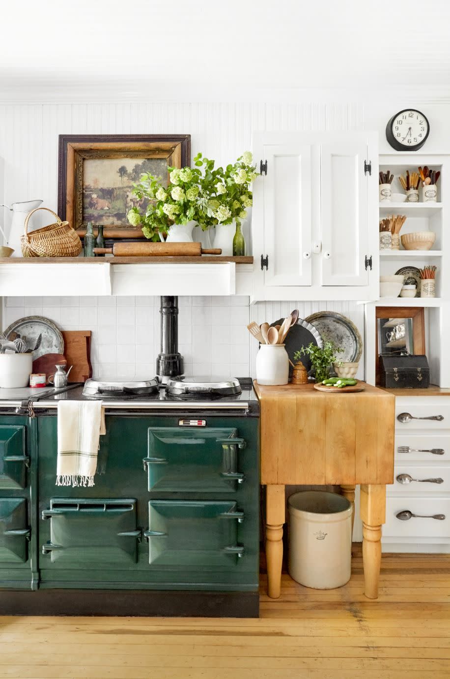 white kitchen with green aga stove, crocks filled with cutlery and kitchen utensil