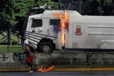 A demonstrator throws a petrol bomb while clashing with riot security forces outside of an Air Force base during a rally against Venezuela's President Nicolas Maduro's Government in Caracas, Venezuela, June 23, 2017. REUTERS/Marco Bello