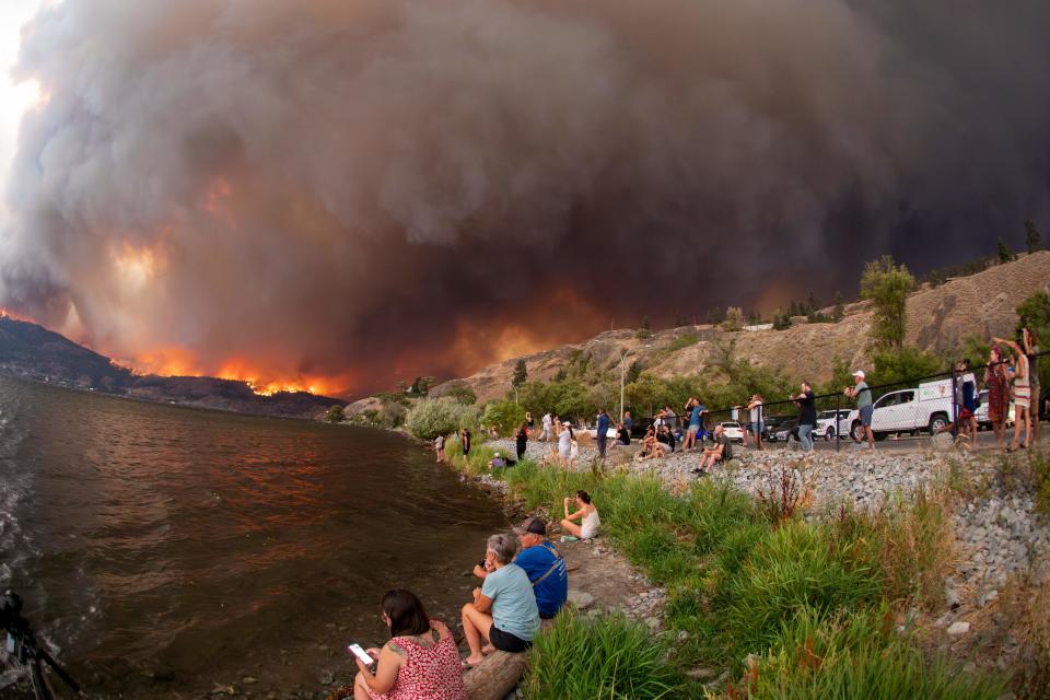 Residents watch the McDougall Creek wildfire in West Kelowna, British Columbia, Canada, on August 17, 2023, from Kelowna. Evacuation orders were put in place for areas near Kelowna, as the fire threatened the city of around 150,000. Canada is experiencing a record-setting wildfire season, with official estimates of over 13.7 million hectares (33.9 million acres) already scorched. Four people have died so far. (Photo by Darren HULL / AFP) (Photo by DARREN HULL/AFP via Getty Images)