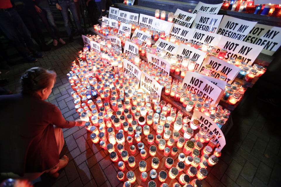 People place candles by posters reading "not my president" during protest in Mostar, Bosnia, Thursday, Oct. 11, 2018. Several thousand Bosnian Croat nationalists have protested the election victory of a moderate politician last weekend in the race for the Croat seat in Bosnia's three-person presidency. The crowd Thursday marched through the ethnically divided southern town of Mostar holding banners reading "Not my president" and "RIP democracy" in protest at the election of Zeljko Komsic." (AP Photo/Amel Emric)