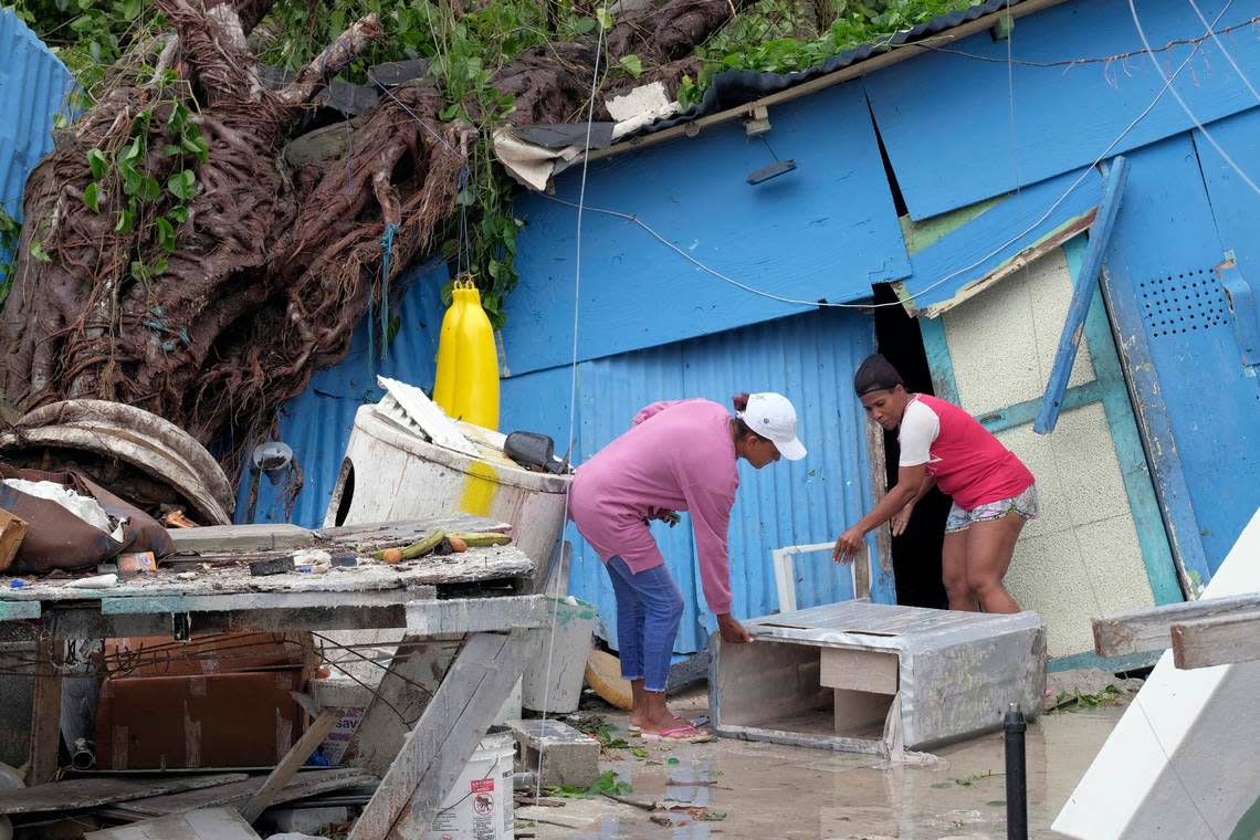 Yesenia Martinez, left, and Dilcia Figaro pick up items scattered by Hurricane Fiona in the Kosovo neighborhood of Punta Cana, Dominican Republic, Monday, Sept. 19, 2022.