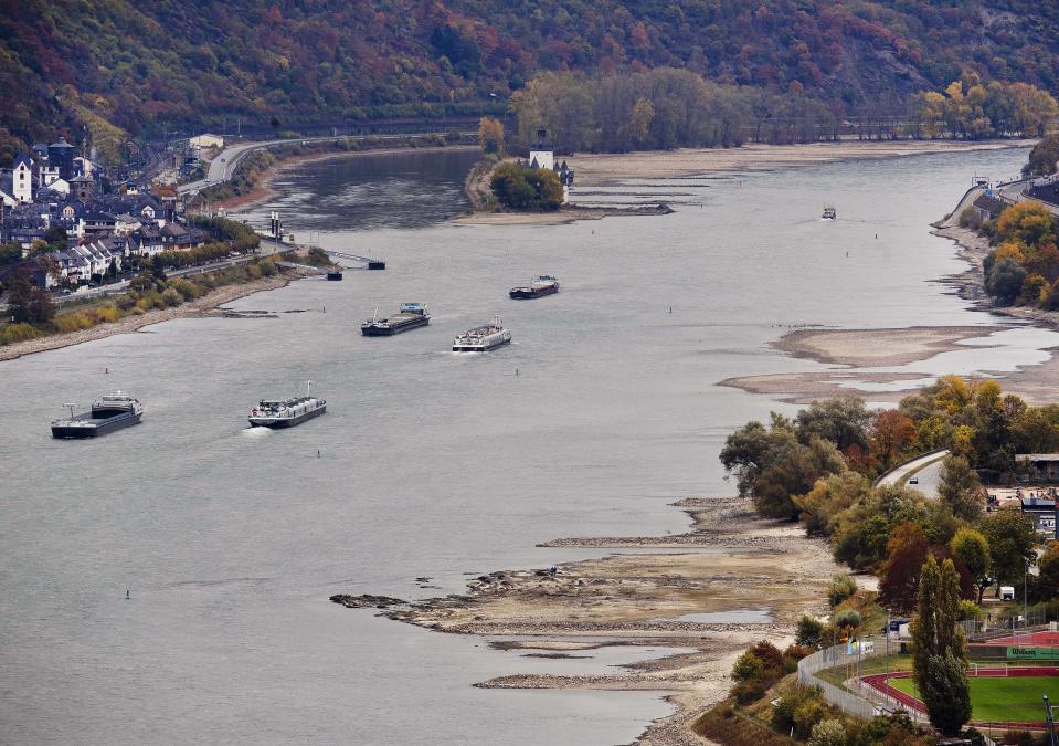 In this Wednesday, Oct.24, 2018 picture cargo ships pass sandbanks in the river Rhine near Oberwesel, Germany, during historically low water levels. A hot, dry summer has left German waterways at record low levels, causing chaos for the inland shipping industry, environmental damage and billions of euros of losses _ a scenario that experts warn could portend things to come as global temperatures rise. (AP Photo/Michael Probst)