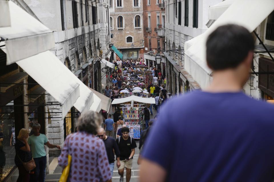 Tourists walk in a crowded street, in Venice, Italy, Wednesday, Sept. 13, 2023. The Italian city of Venice has been struggling to manage an onslaught of tourists in the budget travel era. The stakes for the fragile lagoon city are high this week as a UNESCO committee decides whether to insert Venice on its list of endangered sites. (AP Photo/Luca Bruno)