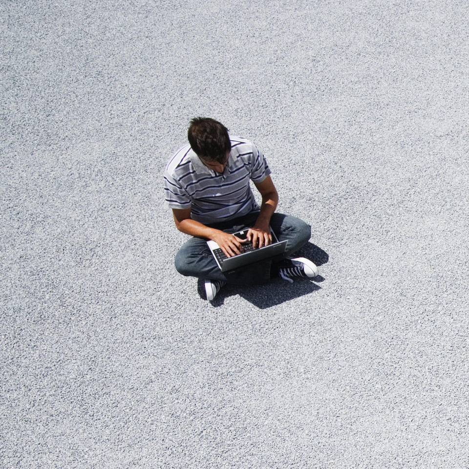 Man sitting on the ground working on his laptop computer (Getty Images)