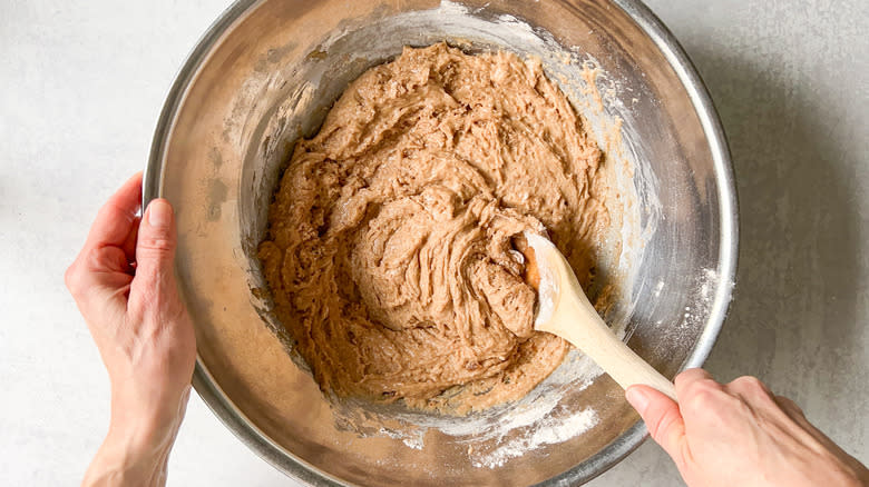 Mixing vegan carrot cake batter in bowl with wooden spoon