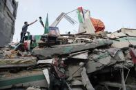 A Palestinian man throws a flag atop the rubble of the home of Hamas Gaza leader Ismail Haniyeh, which Gaza's interior ministry said was hit by a missile fired by Israeli aircraft before dawn on Tuesday, causing damage but no casualties, in Gaza City July 29, 2014. REUTERS/Finbarr O'Reilly