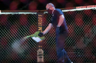 A worker sprays sanitizer in the octagon between bouts during a UFC 249 mixed martial arts competition, Saturday, May 9, 2020, in Jacksonville, Fla. (AP Photo/John Raoux)