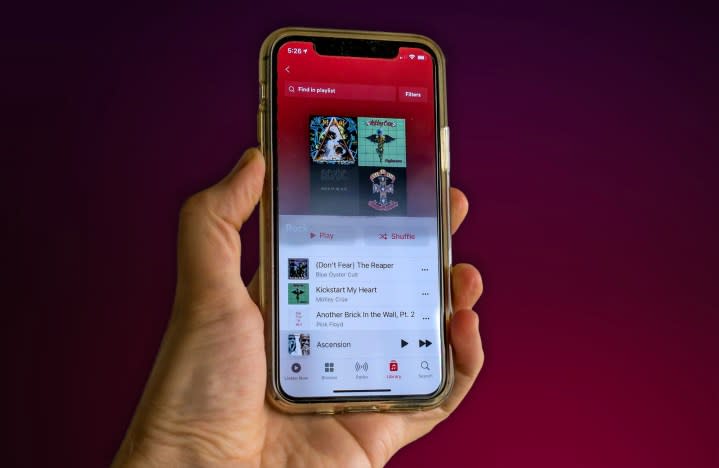 A person holds an iPhone 11 with the Apple Music app open.
