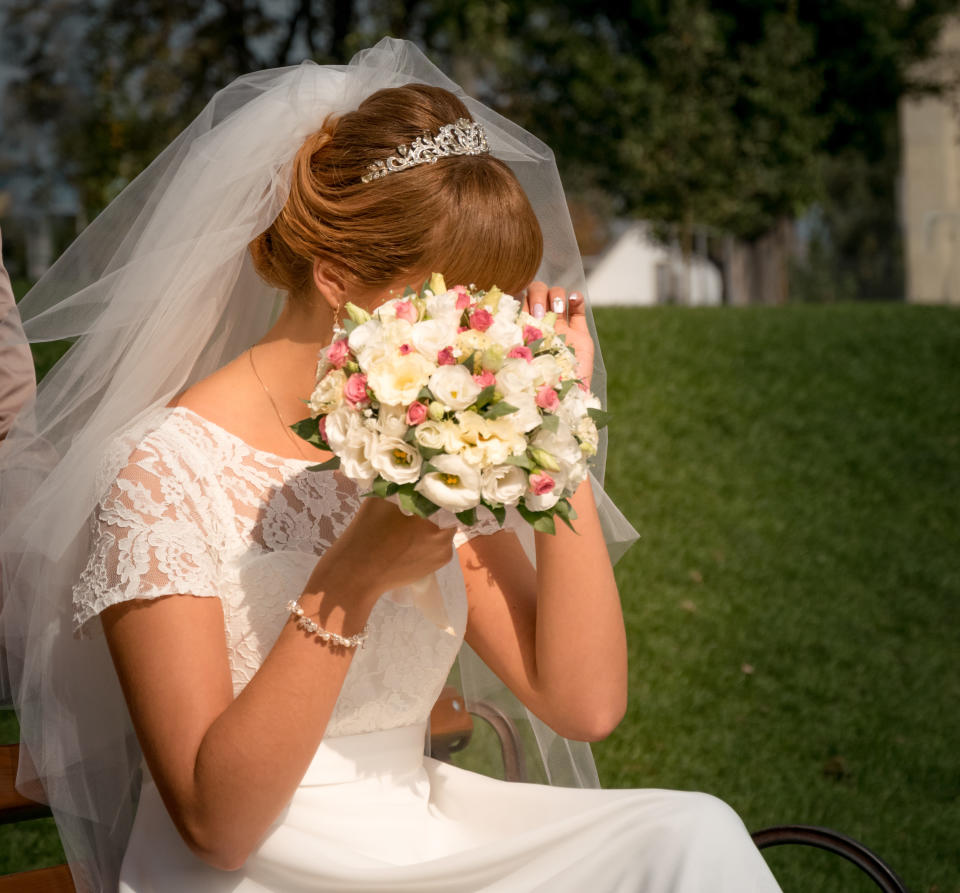 bride crying with a bouquet hiding her face