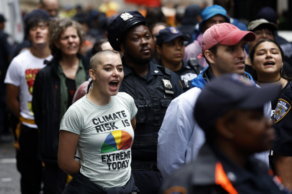 A climate activist continues to chant while under arrest after blockading the Federal Reserve Bank of New York to call for an end to the use of fossil fuels, Monday, Sept. 18, 2023, in New York. (AP Photo/Jason DeCrow)