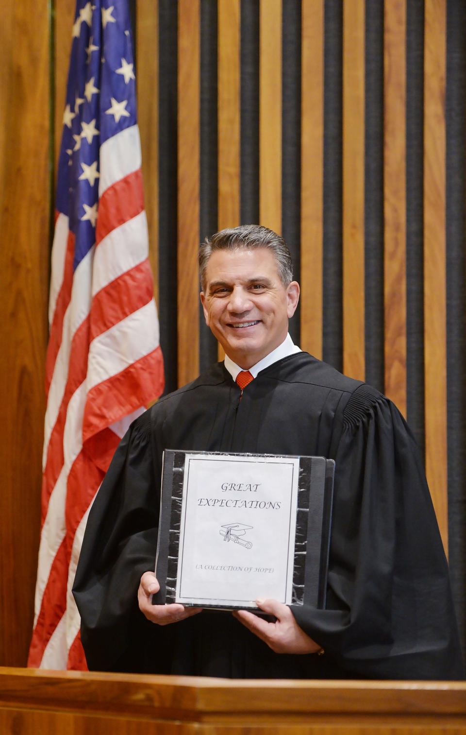 Erie County Judge John Trucilla holds a binder of diplomas and GED certificates from young people he has helped by requiring them to earn a GED or diploma before they can be discharged from court supervision. Trucilla was shown at the Erie County Courthouse in Erie on Feb. 29, 2024.