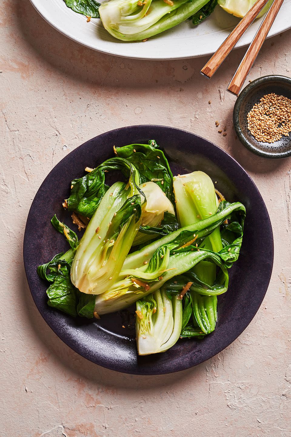 bok choy topped with ginger and sesame seeds in a black bowl