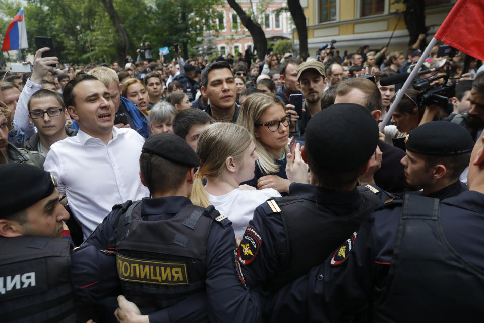 Russian opposition candidate and lawyer at the Foundation for Fighting Corruption Lyubov Sobol, center, and candidate Ivan Zhdanov, 2nd left, stand with other protesters in front of police line during a protest in Moscow, Russia, Sunday, July 14, 2019. Around 1,000 people have gathered in central Moscow to demand that opposition candidates be included on ballots for an upcoming city parliament election in September. (AP Photo/Pavel Golovkin)