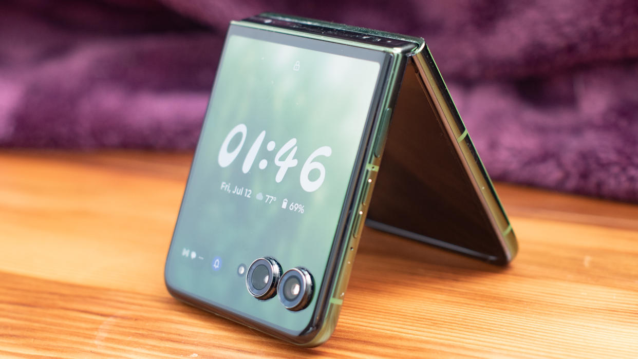  Motorola Razr Plus 2024 in green standing like a tent with a clock on its face. 