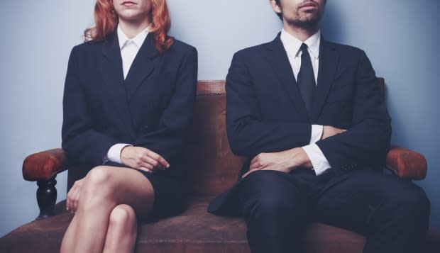 Two sharply dressed business people are waiting on a sofa with a serious expression on their faces. Maybe they're waiting to ent