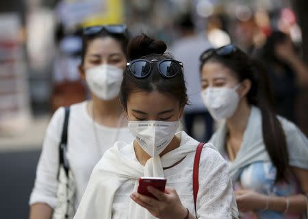 A tourist wearing a mask to prevent contracting Middle East Respiratory Syndrome (MERS) uses her mobile phone at Myeongdong shopping district in central Seoul, South Korea, June 10, 2015. REUTERS/Kim Hong-Ji